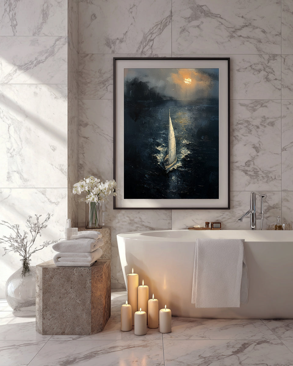 Framed sailing artwork displayed above a bathtub in a marble bathroom with candles and soft natural light.