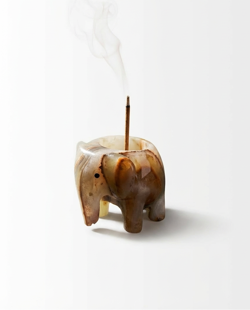 Elephant-shaped incense holder with smoke on a white background