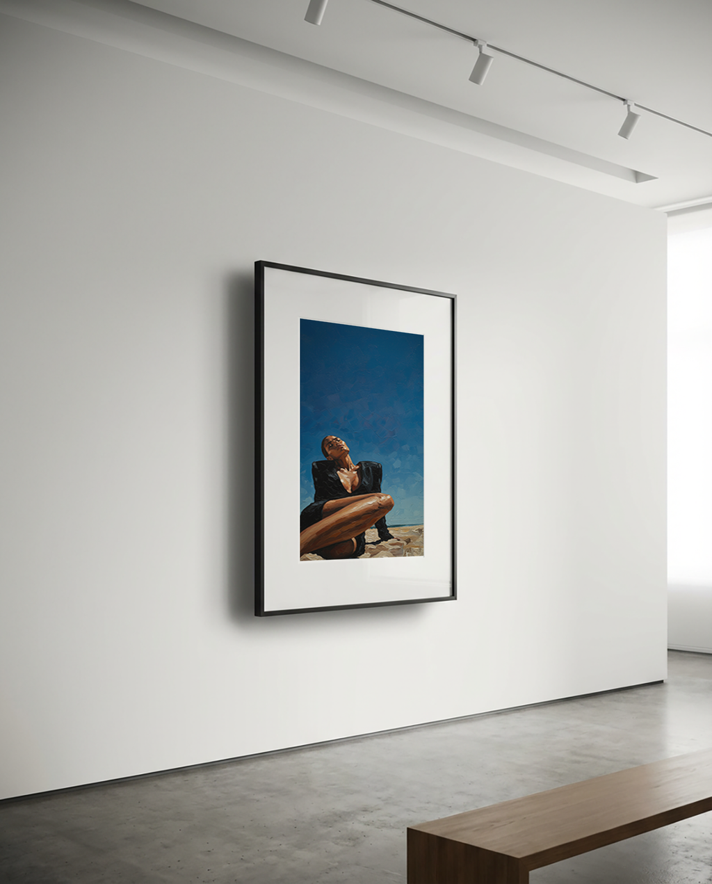 Framed artwork of a person sitting on a beach with a blue sky, displayed on a white wall.