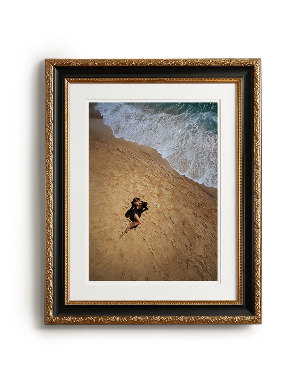 Framed artwork of a person lying on a beach with waves in the background