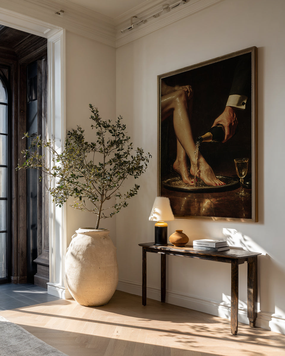 Decorative interior with a large vase, lamp, and painting on a wall.