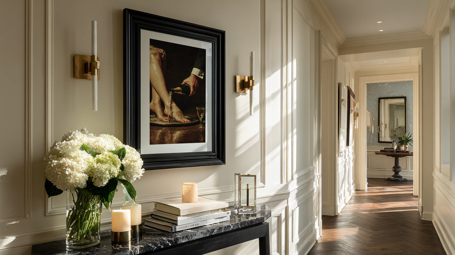 Elegant interior with a framed picture, candles, and flowers on a table.