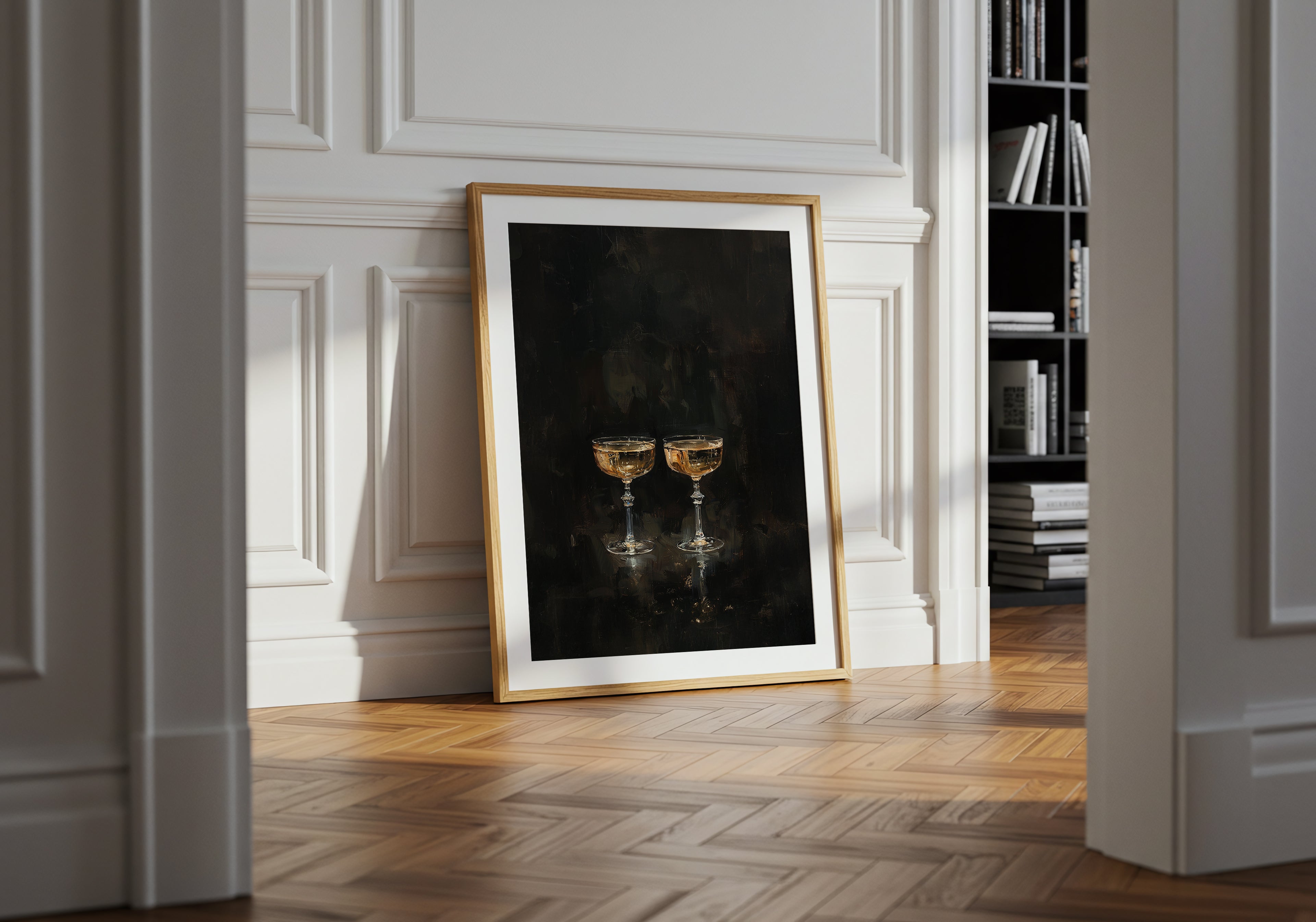 Framed artwork of two gold goblets on a black background in a room with white walls and wooden floor.