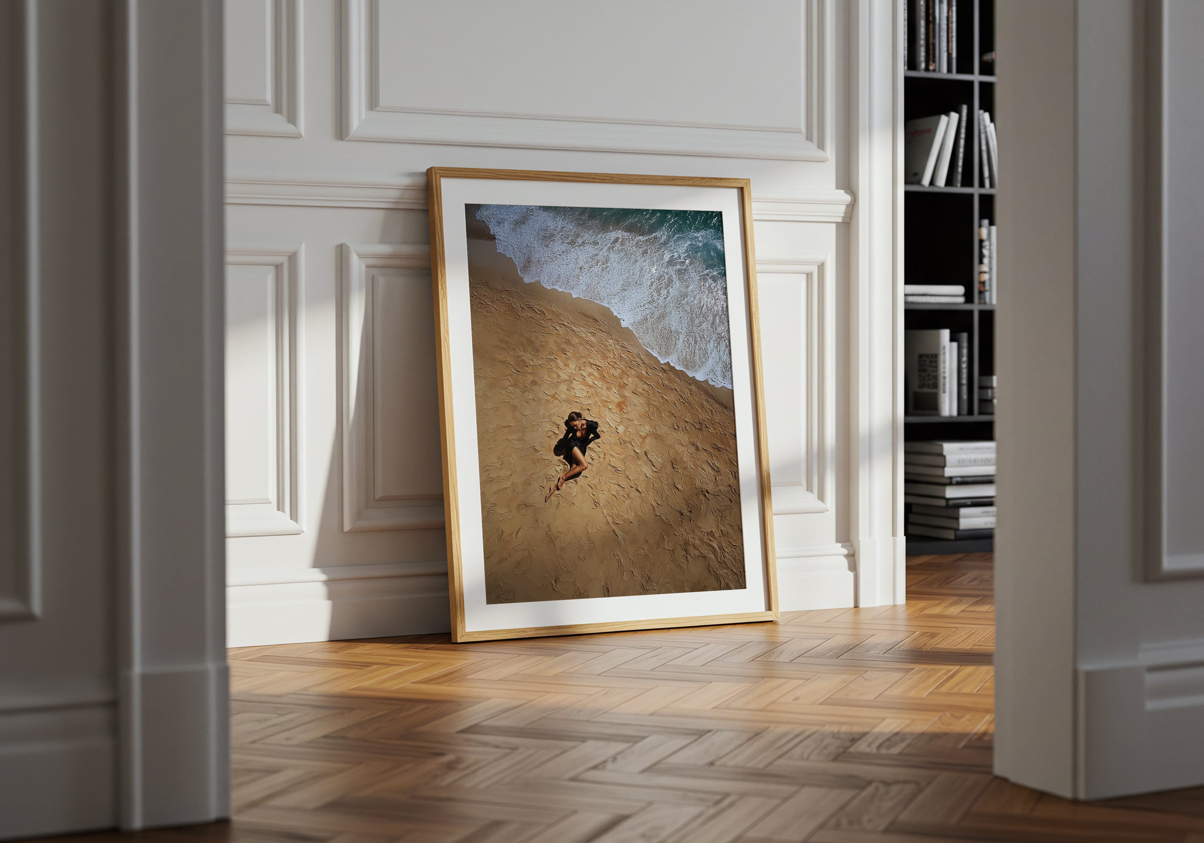 Framed artwork on a wall in a room with wooden flooring and a bookshelf.